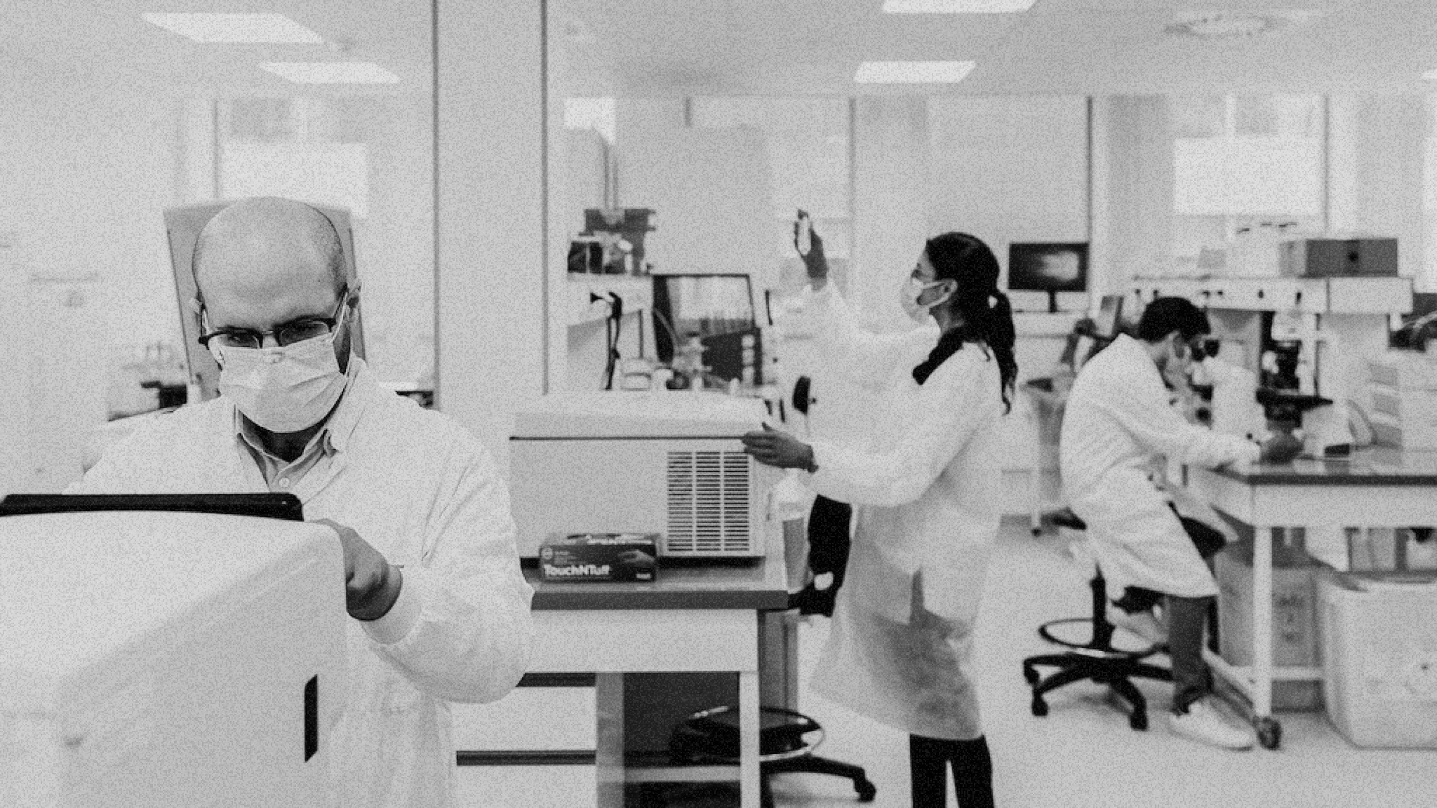 Several scientists doing science-y things in a lab.