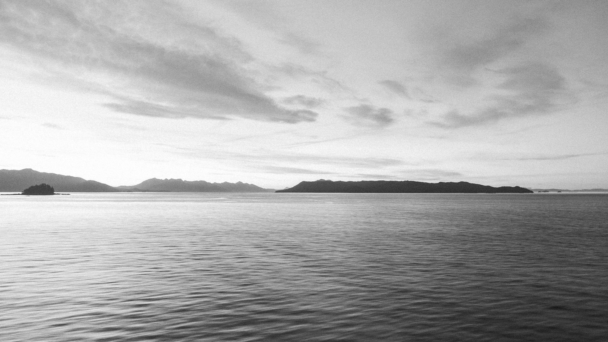 An ocean view at sunset with low mountains peaking out in the distance, creating a serene and calming vibe.